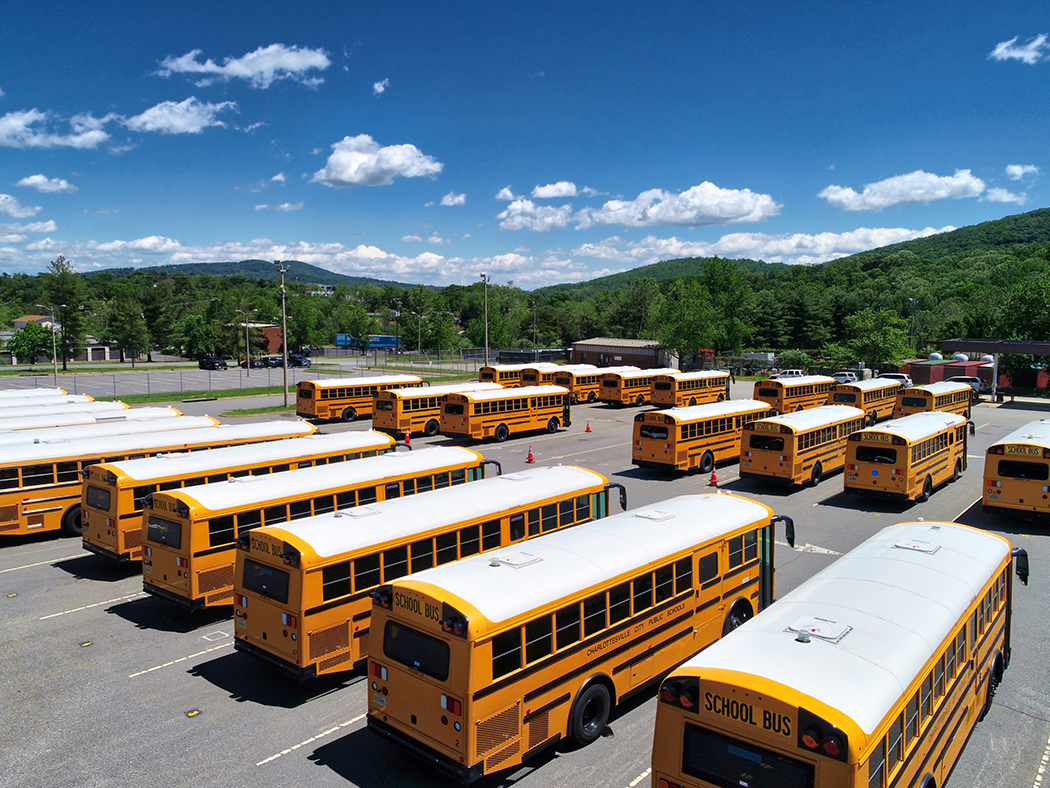 Fleet of yellow school buses in a parking lot under a sunny blue sky