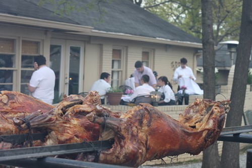 Three lambs roasting while chefs prepare for the Friends of Beard Dinner.